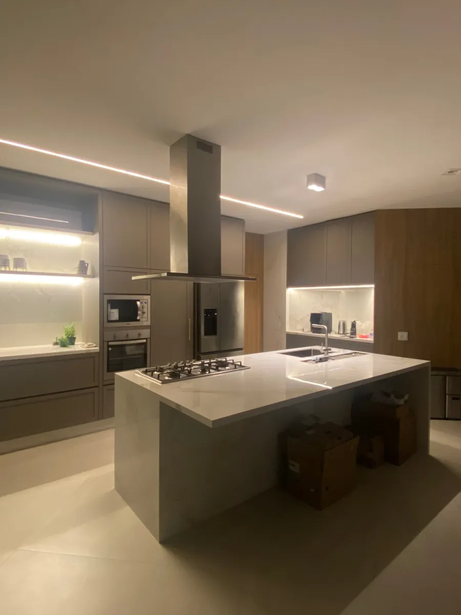 Cozinha com ilha central em pedra, marcenaria sob medida e iluminação embutida
