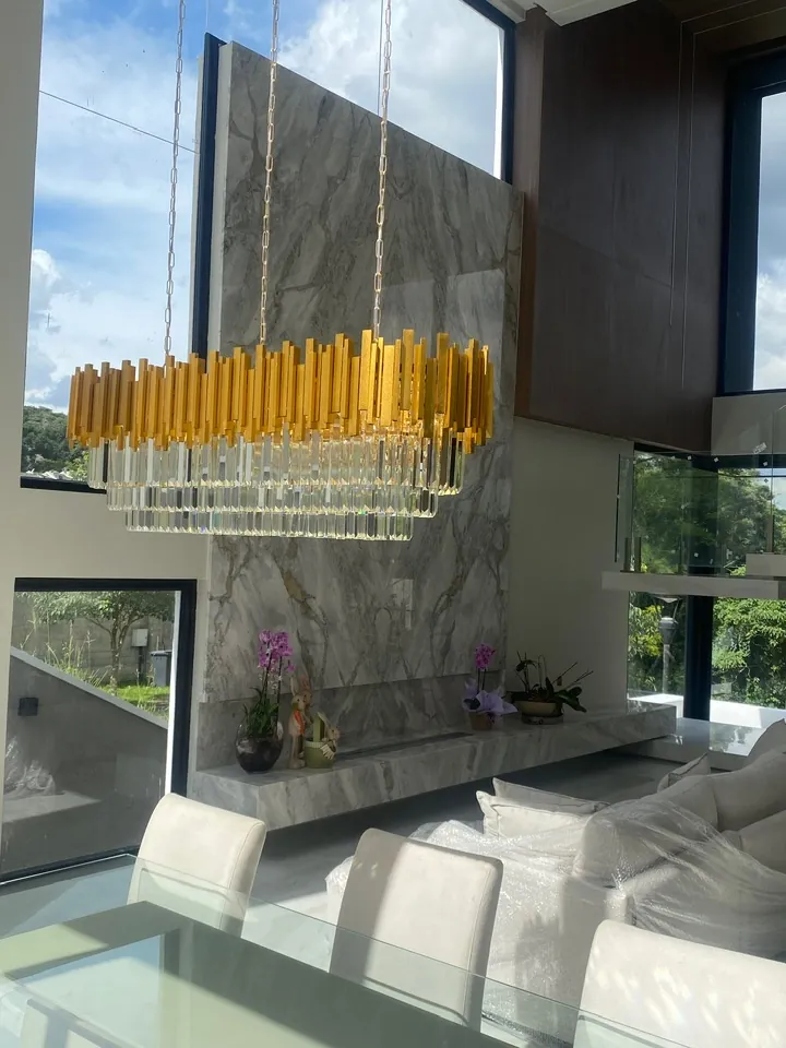 Living com lustre de cristal, parede de mármore e vista para o jardim