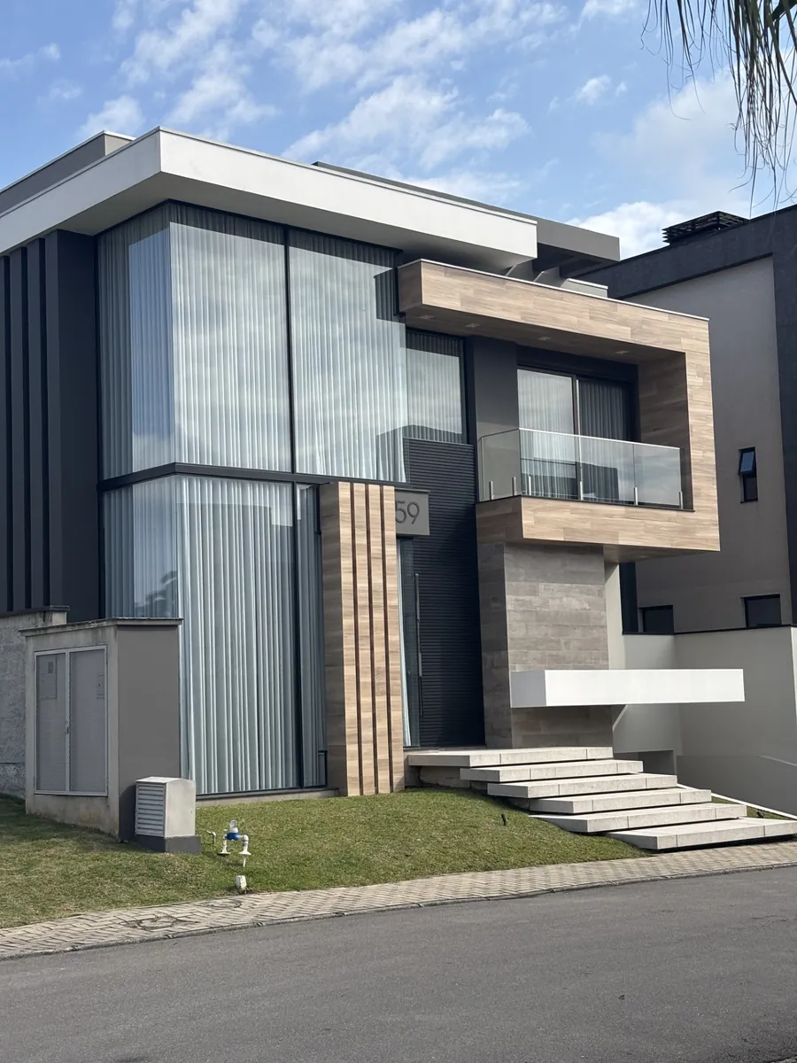 Fachada com revestimento em madeira, pele de vidro e volume em concreto, sob céu azul