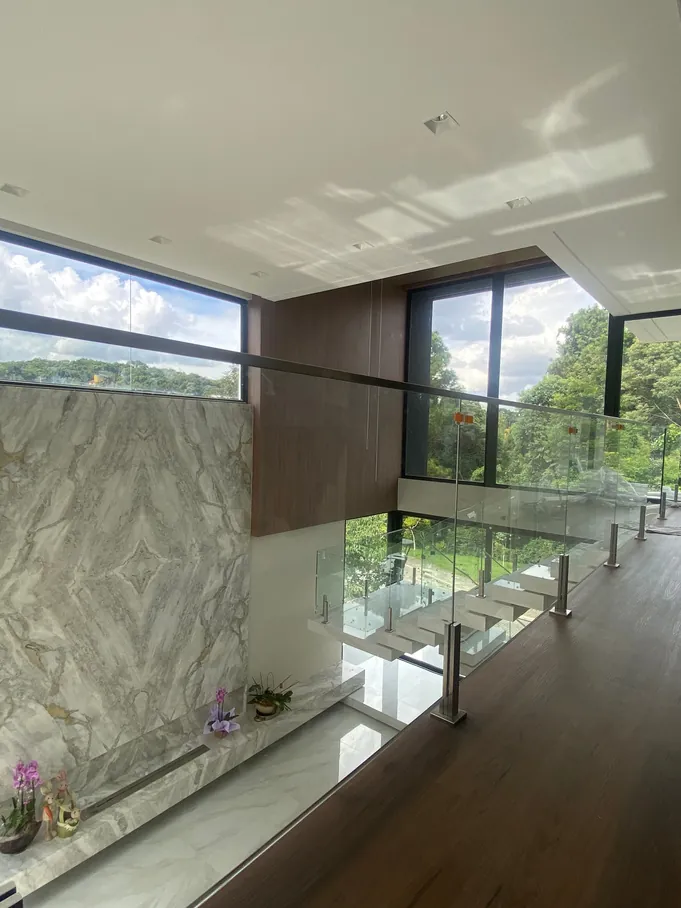 Mezanino com piso de madeira, parede de mármore e esquadria de piso a teto